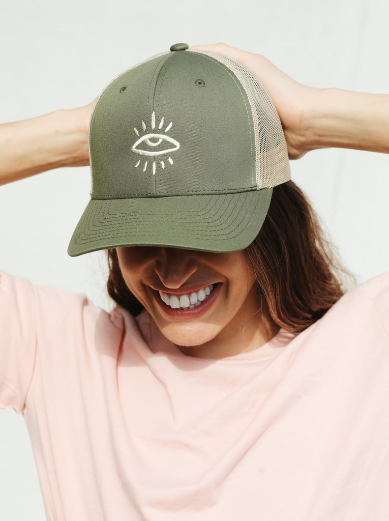 Green and tan trucker hat featuring The Mindry logo on the front. Worn by model facing forward.
