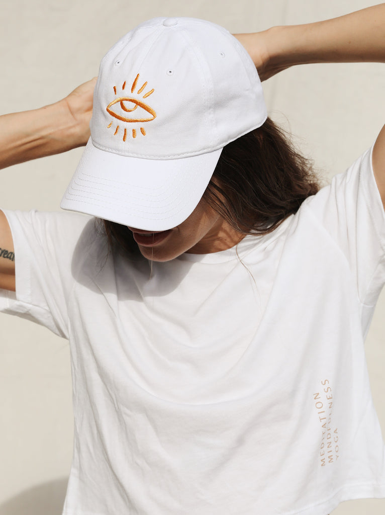 White colored dad hat featuring The Mindry logo on the front. Worn by model facing forwards and to the left.