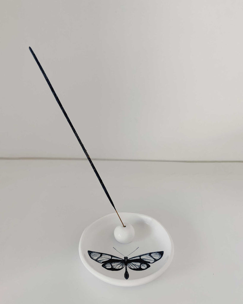 White incense burning dish with a black butterfly on the dish. 